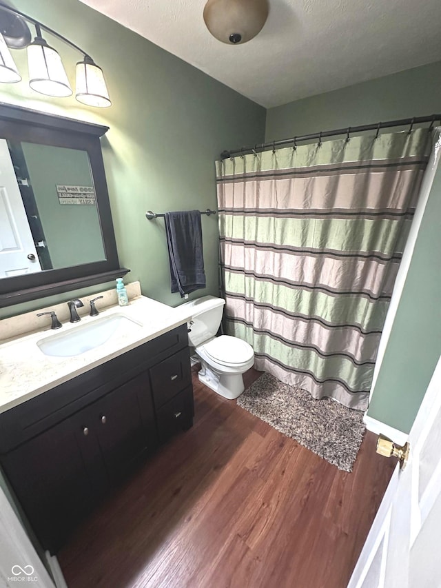 bathroom featuring vanity, hardwood / wood-style floors, a textured ceiling, and toilet