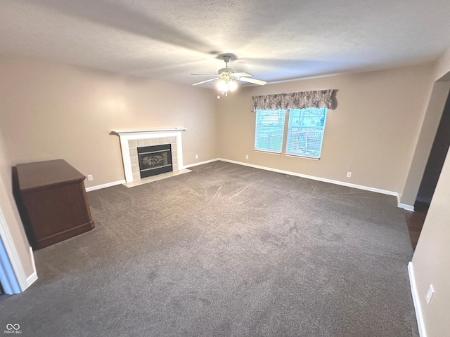 unfurnished living room featuring ceiling fan, a textured ceiling, a tile fireplace, and dark colored carpet