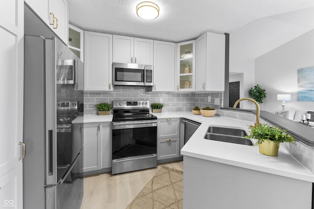 kitchen with sink, tasteful backsplash, light hardwood / wood-style flooring, appliances with stainless steel finishes, and white cabinets