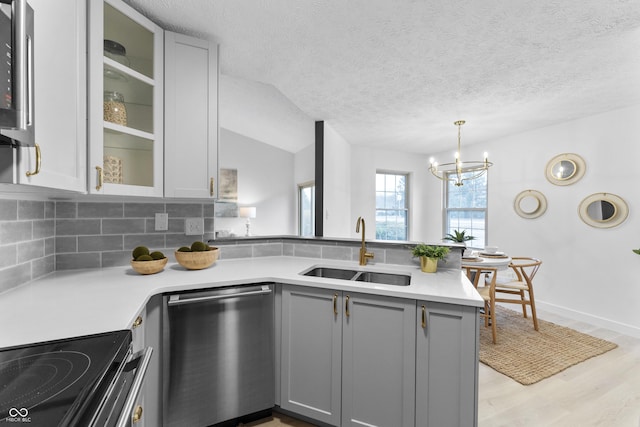 kitchen with sink, tasteful backsplash, vaulted ceiling, gray cabinets, and dishwasher