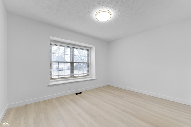 empty room with light hardwood / wood-style floors and a textured ceiling