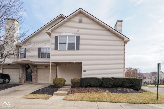 multi unit property with driveway, brick siding, a chimney, and an attached garage