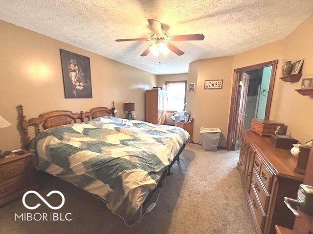 bedroom with light colored carpet, ceiling fan, and a textured ceiling