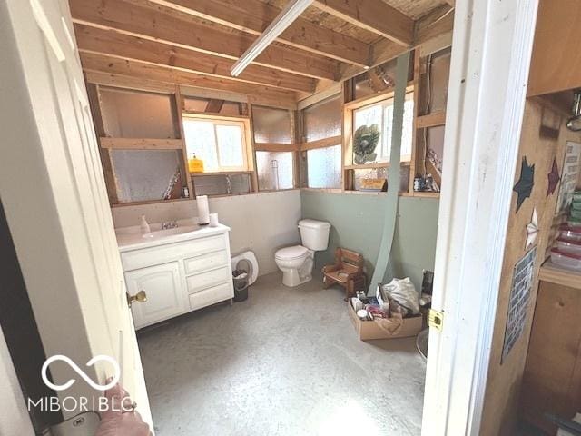 bathroom featuring concrete floors, vanity, and toilet