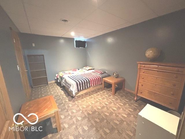 carpeted bedroom with a paneled ceiling, visible vents, and baseboards