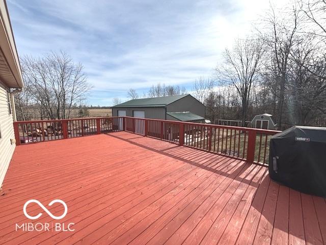 wooden terrace featuring an outbuilding, a grill, and a shed