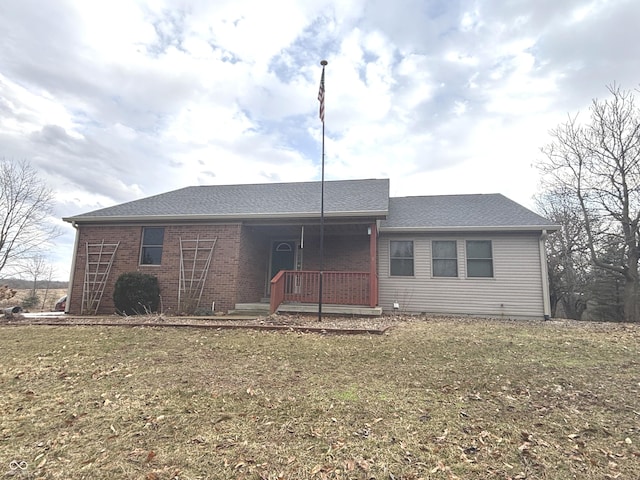 view of front of home featuring a front yard, brick siding, and roof with shingles