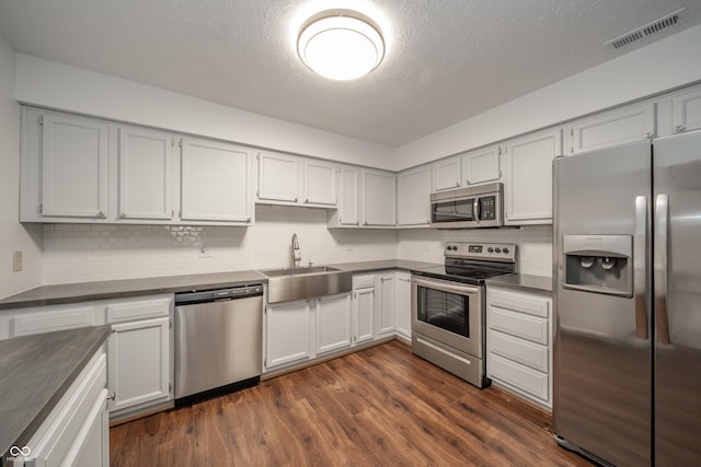 kitchen featuring stainless steel appliances, sink, dark hardwood / wood-style flooring, and decorative backsplash