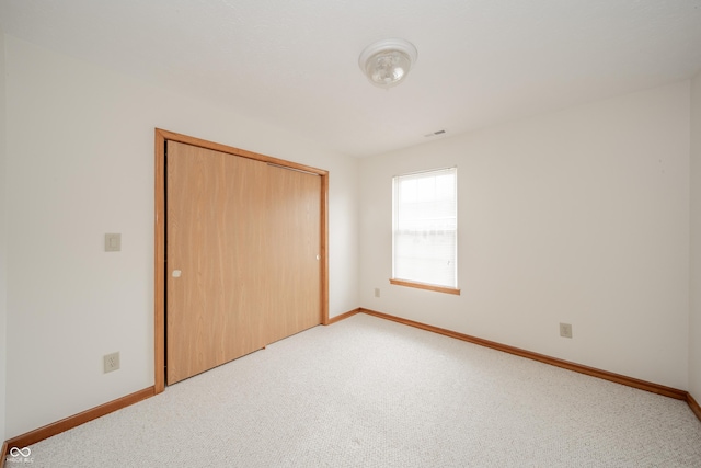 unfurnished bedroom featuring a closet and light carpet