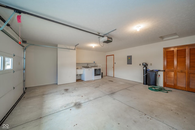 garage with washing machine and clothes dryer, a garage door opener, electric panel, and sink