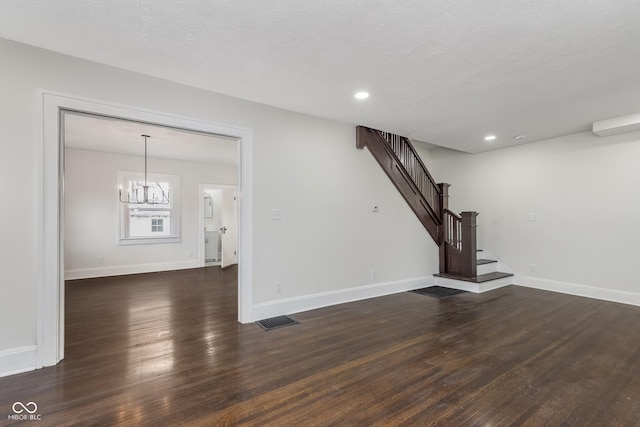 unfurnished living room with dark hardwood / wood-style flooring, a chandelier, and a textured ceiling