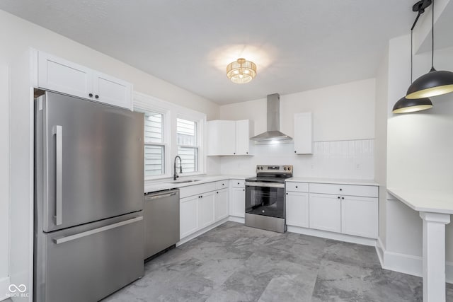 kitchen featuring white cabinetry, sink, hanging light fixtures, stainless steel appliances, and wall chimney range hood