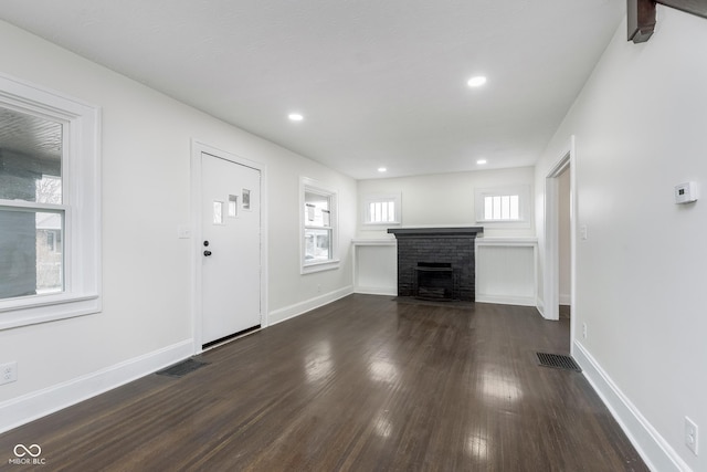 unfurnished living room featuring dark hardwood / wood-style floors and a brick fireplace