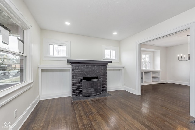 unfurnished living room with a brick fireplace and dark hardwood / wood-style floors