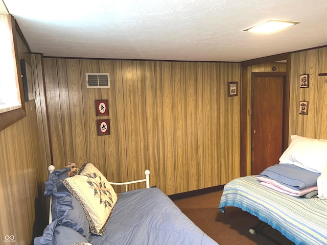 carpeted bedroom featuring wood walls