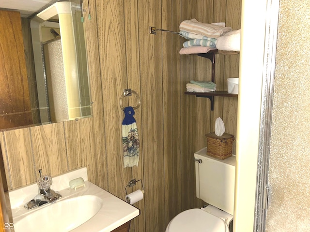 bathroom featuring vanity, wooden walls, and toilet