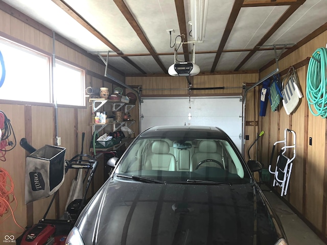 garage featuring a garage door opener and wooden walls