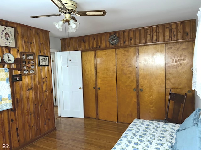 bedroom with dark hardwood / wood-style floors, a closet, and wood walls