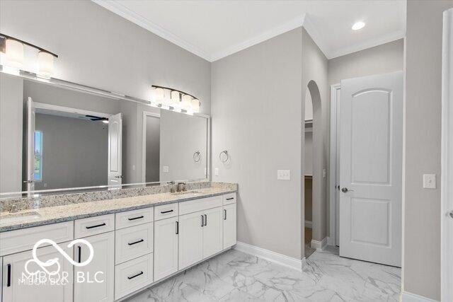 full bathroom featuring marble finish floor, double vanity, ornamental molding, a sink, and baseboards