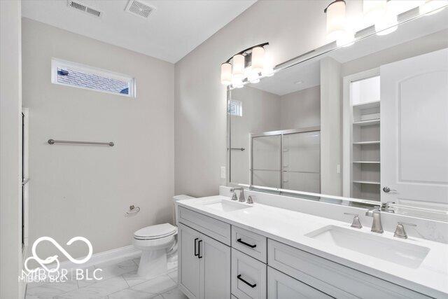 bathroom with visible vents, a stall shower, a sink, and toilet