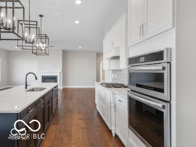 kitchen with a sink, light countertops, appliances with stainless steel finishes, decorative backsplash, and dark wood finished floors