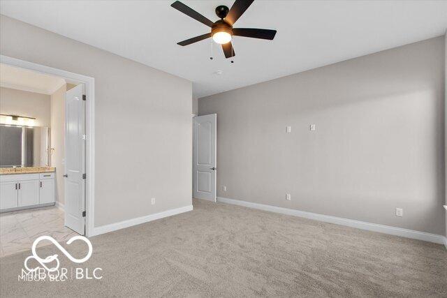 unfurnished bedroom featuring ensuite bath, baseboards, a ceiling fan, and light colored carpet