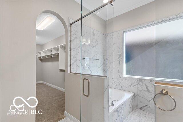 bathroom with a garden tub, a shower stall, and baseboards