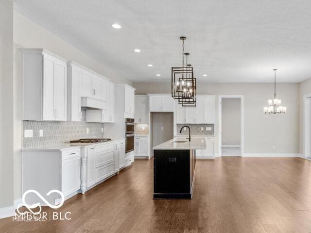 kitchen featuring dark wood-style floors, a notable chandelier, light countertops, premium range hood, and a sink