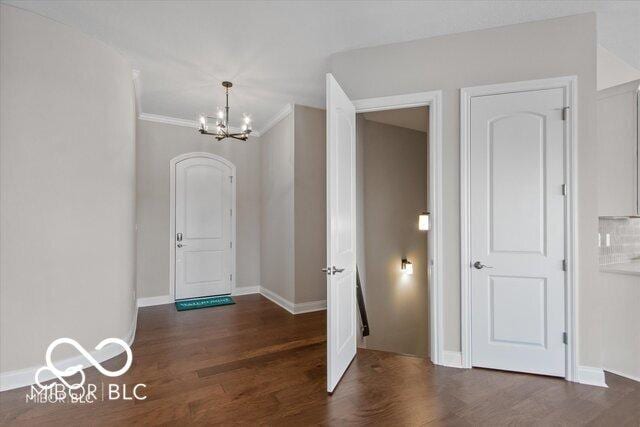 entrance foyer featuring crown molding, baseboards, a chandelier, and wood finished floors