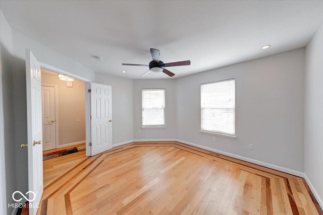 empty room featuring recessed lighting, a ceiling fan, baseboards, and light wood finished floors