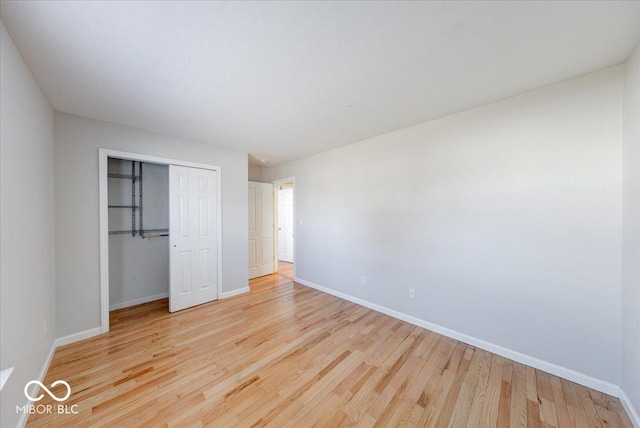 unfurnished bedroom featuring wood finished floors, a closet, and baseboards