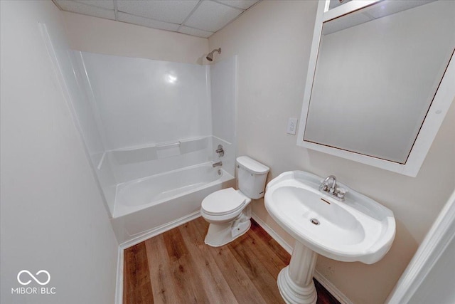 bathroom with toilet, a sink, a drop ceiling, shower / tub combination, and wood finished floors