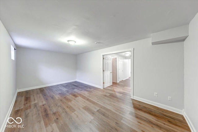 spare room with baseboards and wood finished floors