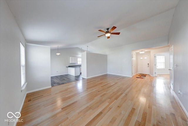 unfurnished living room featuring baseboards, light wood-style floors, ceiling fan, and vaulted ceiling