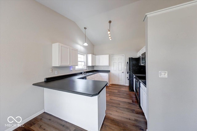 kitchen with white cabinetry, dark countertops, a peninsula, and a sink