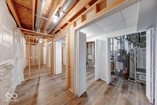 unfinished basement with water heater and wood finished floors