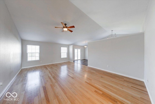 empty room featuring vaulted ceiling, baseboards, ceiling fan, and wood finished floors