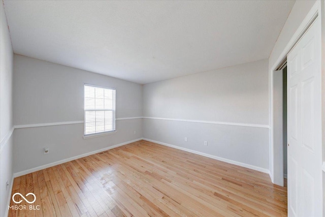 spare room with baseboards and light wood-style floors