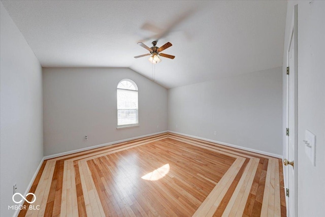 empty room featuring vaulted ceiling, baseboards, ceiling fan, and hardwood / wood-style flooring