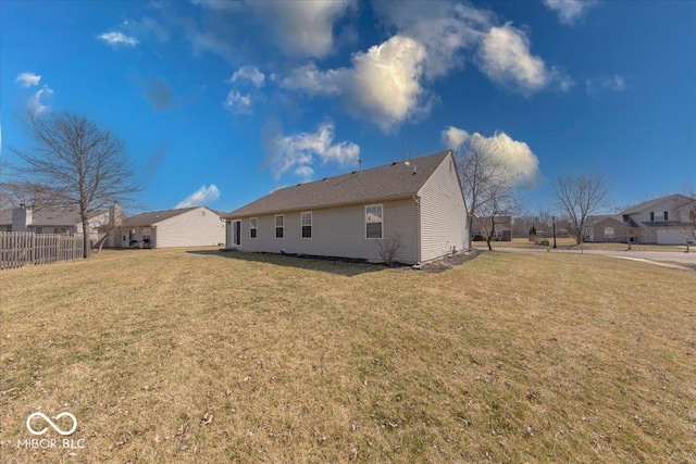 rear view of property featuring a yard and fence