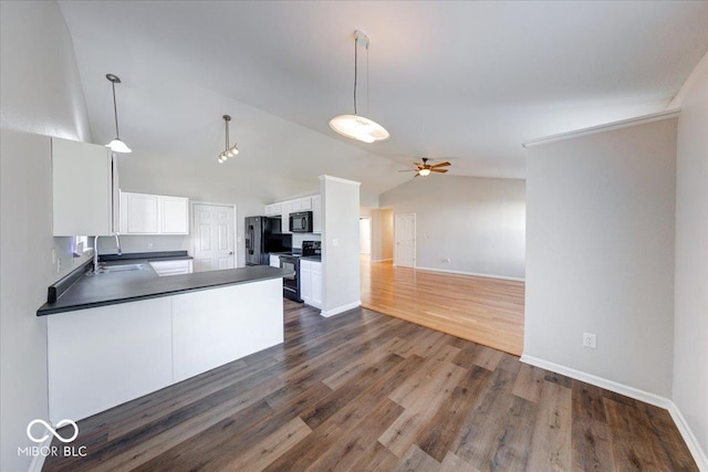 kitchen with dark countertops, open floor plan, black appliances, a ceiling fan, and a sink