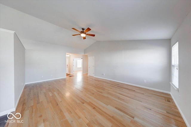 spare room featuring vaulted ceiling, light wood-style flooring, a ceiling fan, and baseboards