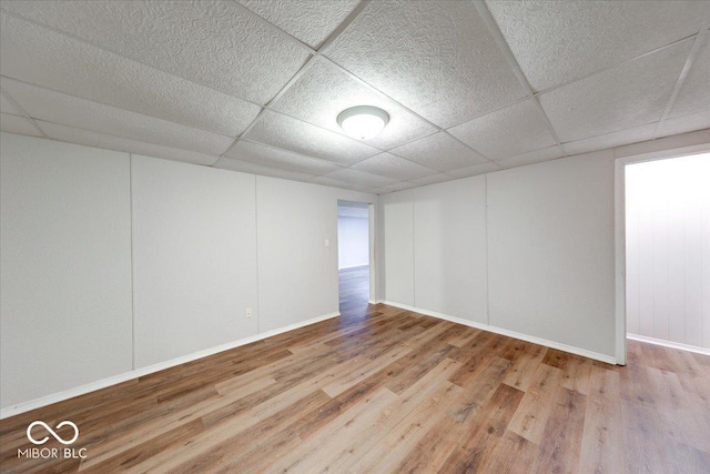 empty room featuring wood finished floors, baseboards, and a drop ceiling