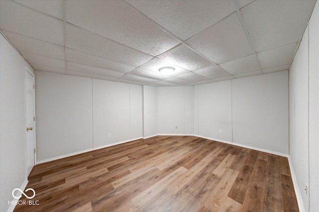 interior space featuring a drop ceiling, baseboards, and wood finished floors