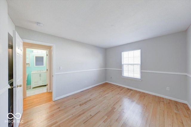 spare room featuring light wood-type flooring and baseboards