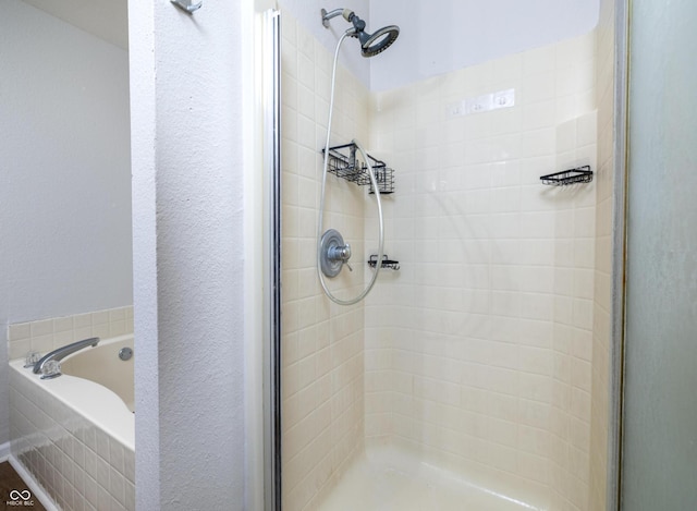 bathroom featuring a shower stall and a bath