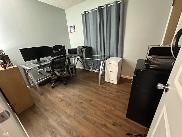 home office with a textured ceiling, dark wood-type flooring, and baseboards