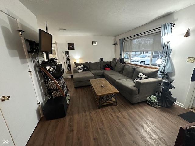 living room featuring a textured ceiling, baseboards, and wood finished floors