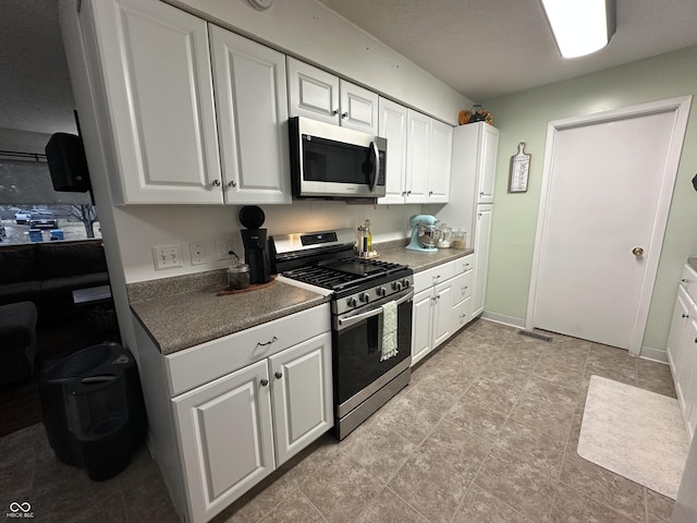 kitchen with baseboards, stainless steel appliances, visible vents, and white cabinets