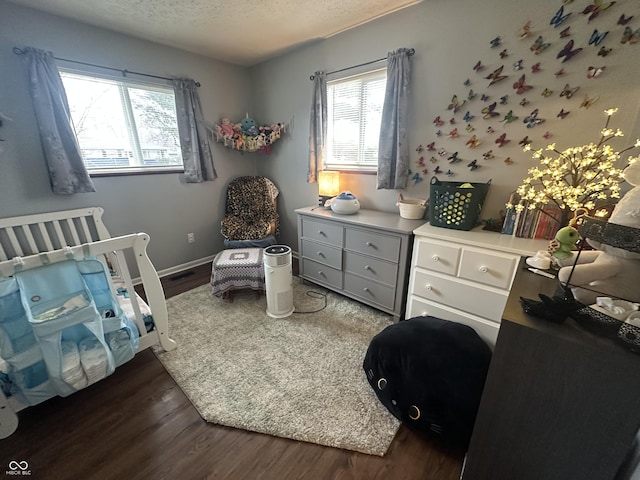 bedroom with dark wood-style floors, baseboards, and a textured ceiling